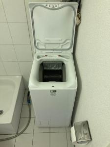 a white toilet with its seat up in a bathroom at 1 Flat-Room Bern in Bern