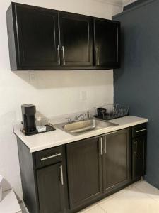 a kitchen with black cabinets and a sink at Sweet Escape Cozy Studio in Fort Lauderdale