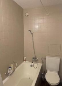 a bathroom with a white tub and a toilet at Studio, proche des pistes et des commerces in Vionnaz