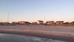 a group of houses on a beach with a fence at carlsens hotel in Vesterø Havn