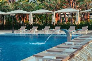 a swimming pool with chaise lounge chairs and a fountain at Bounty Hotel in Golem