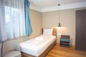 a bedroom with a bed and a chair and a window at ASD Hotel in Filderstadt