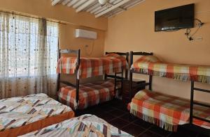 a room with three bunk beds and a flat screen tv at Hostal Haziel in Salinas