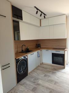 a kitchen with white cabinets and a washer and dryer at Miła Przystań in Debrzno