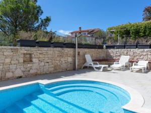 a swimming pool with two chairs and a stone wall at R&G Serenity Apartment in Ližnjan
