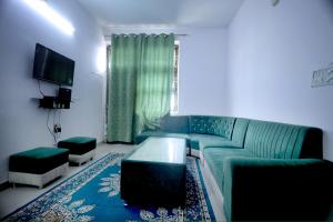 a living room with a green couch and a tv at Tajiva Stay in Agra