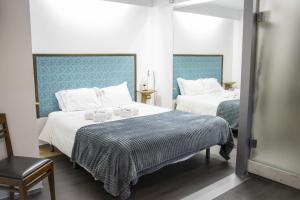 a bedroom with two beds with white sheets and a chair at Collector's Home in Braga