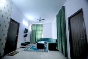 a living room with green curtains and a blue couch at Tajiva Stay in Agra