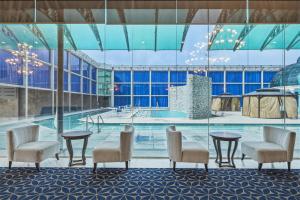 a swimming pool with chairs and tables in a building at Grand Tuscany Hotel in Houston +15 photos