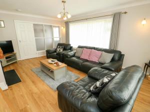 a living room with a leather couch and a table at Min Y Cae in Cemaes Bay