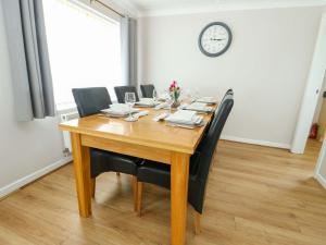 a dining room table with black chairs and a clock on the wall at Min Y Cae in Cemaes Bay