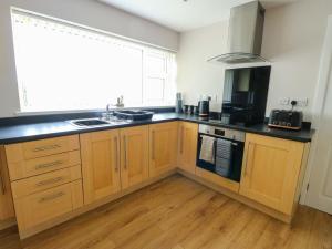 a kitchen with wooden cabinets and a sink and a window at Min Y Cae in Cemaes Bay +15 photos