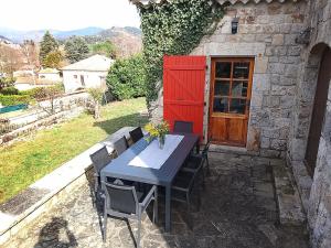 a table and chairs in front of a building with a red door at La Maison du Bonheur in Jaujac