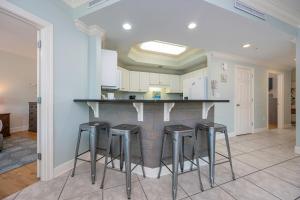 a kitchen with a bar with stools around it at Phoenix on the Bay 1326 condo in Orange Beach