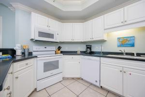 a white kitchen with white cabinets and a microwave at Phoenix on the Bay 1326 condo in Orange Beach