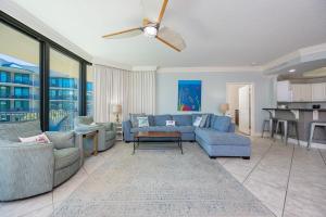 a living room with blue furniture and a ceiling fan at Phoenix on the Bay 1326 condo in Orange Beach