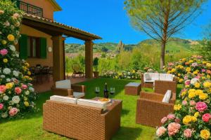 a garden with chairs and a table and flowers at Villa delle rose Brisighella in Brisighella