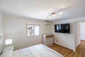 a white bedroom with a bed and a flat screen tv at Villa Las Norias in Tazacorte