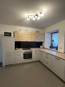 a kitchen with white cabinets and a stove top oven at Ferienhaus am Rad- und Wanderweg in Nerdlen