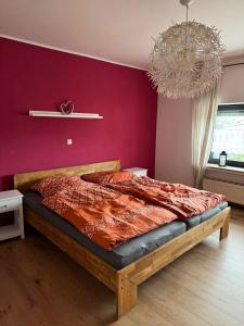 a bedroom with a bed with a red wall at Ferienhaus am Rad- und Wanderweg in Nerdlen