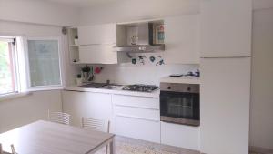 a white kitchen with a table and a refrigerator at Relax e Mare a Bellaria in Bellaria-Igea Marina