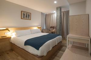 a bedroom with a large bed and a desk and a table at A Casa do Tella e Rosalía in Portosin