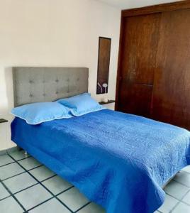 a bedroom with a blue bed and a wooden door at Tu depa en SLP in San Luis Potosí