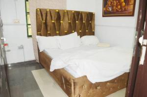 a bed with a wooden headboard and white sheets at Lifeconcep apartment and lodge in Ibadan
