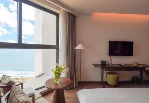a living room with a couch and a large window at Mandala Wins Apec Mũi Né in Mui Ne
