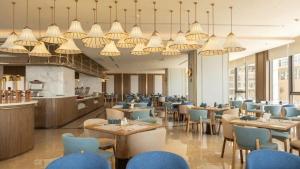 a restaurant with tables and blue chairs and chandeliers at Mandala Wins Apec Mũi Né in Mui Ne