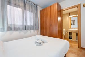 a bedroom with a white bed and a bathroom at Hauzify I Apartaments Bellaire in Blanes