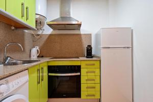 a kitchen with yellow cabinets and a white refrigerator at Hauzify I Apartaments Bellaire in Blanes +13 photos