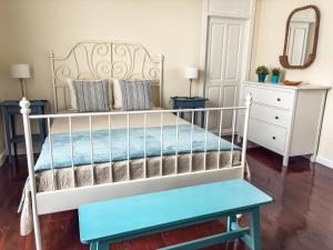 a white bed with a blue bench in a bedroom at Donde Conchita, cerca del aeropuerto norte in Las Lagunas