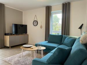 a living room with a blue couch and a tv at Dahmer Strand 1 - LÜTT HUIS in Dahme