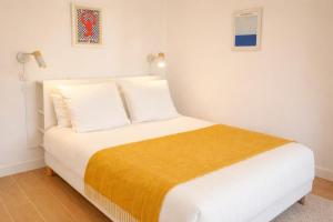 a bedroom with a white bed with a yellow blanket at Le Blue Hole - Appartement de charme Digoin in Digoin +2 photos