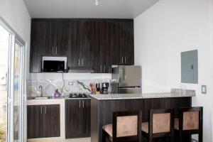 a kitchen with wooden cabinets and a counter with chairs at Kirara's House in Chanmico