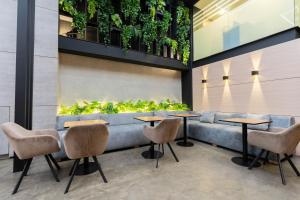 a restaurant with a bench with tables and chairs and plants at Hotel Time Oclock Medellin in Medellín