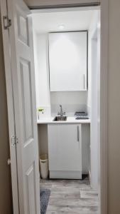 a white kitchen with a sink and a mirror at Single Room near Science Park in Histon