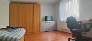 a bedroom with a bed and a tv and a chair at Privatzimmer Ahlten in Lehrte