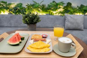 a table with two plates of food and a cup of orange juice at Hotel Time Oclock Medellin in Medellín