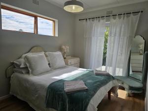 a bedroom with a bed with a chair and a window at Graatjie in Kleinmond