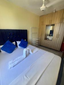 a bedroom with a large white bed with blue pillows at Guest Favorite 1BDR with Washer, Netflix, Parking & Hot Shower 2547,96,065,022 in Mombasa