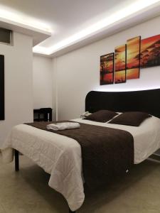 a bedroom with a large bed with three paintings on the wall at HOSTAL MURGEON BOUTIQUE in Quito