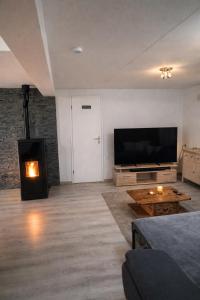 a living room with a fireplace and a flat screen tv at Juralodgespa Chalet Emma in Courrendlin