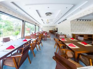 a restaurant with wooden tables and chairs and windows at The Grand Moon River Hotel in Kataragama