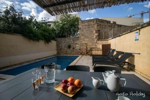 a table with a plate of fruit on it next to a pool at Ta Guzeppi Xaghra in Xagħra