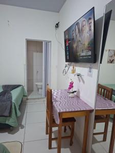 a living room with a table and a tv on the wall at cantinho da Raq,um quarto SUÍTE com ar condicionado duas camas de casal perto doAeroporto, UEPA, Rodoviaria, magueirao, UFPA,parque ambiental, in Belém
