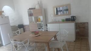 a kitchen with a wooden table and white chairs at Refugio del Limonero - Colonial y Cercano in Córdoba