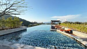 a infinity pool in a vineyard with chairs in the water at 6th Avenue Surin by Win217 in Surin Beach