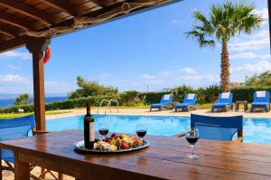 a table with a plate of food and a bottle of wine at Bella Villa with Private Pool & Sea View Ideal for Groups in Vaia